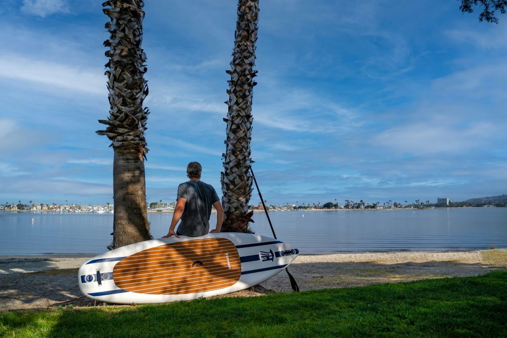 Man leaning on a Paddleboard looking at the water. 