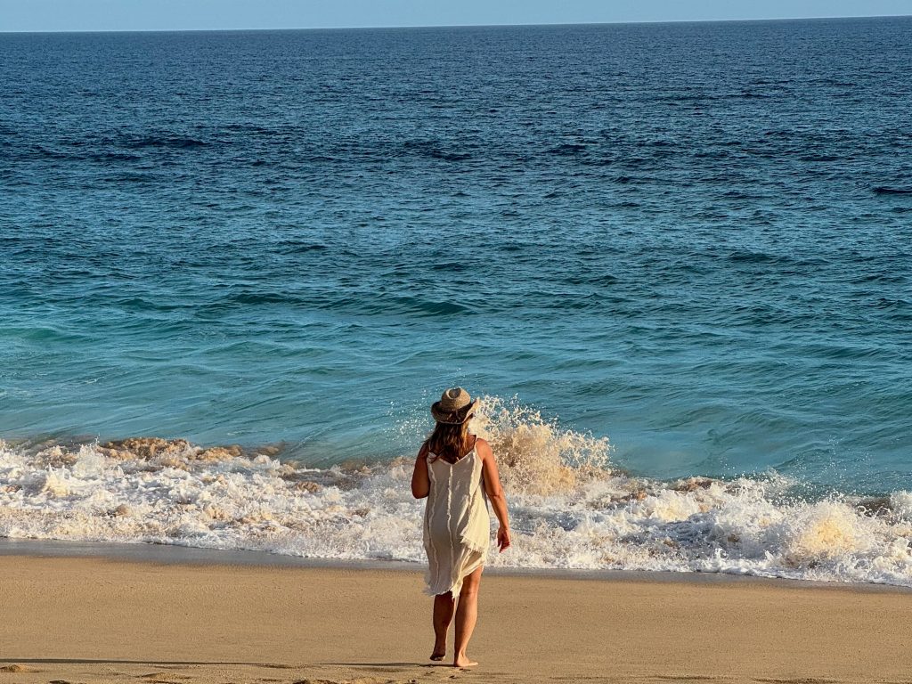 woman walking toward ocean on sand at Hacienda del Mar