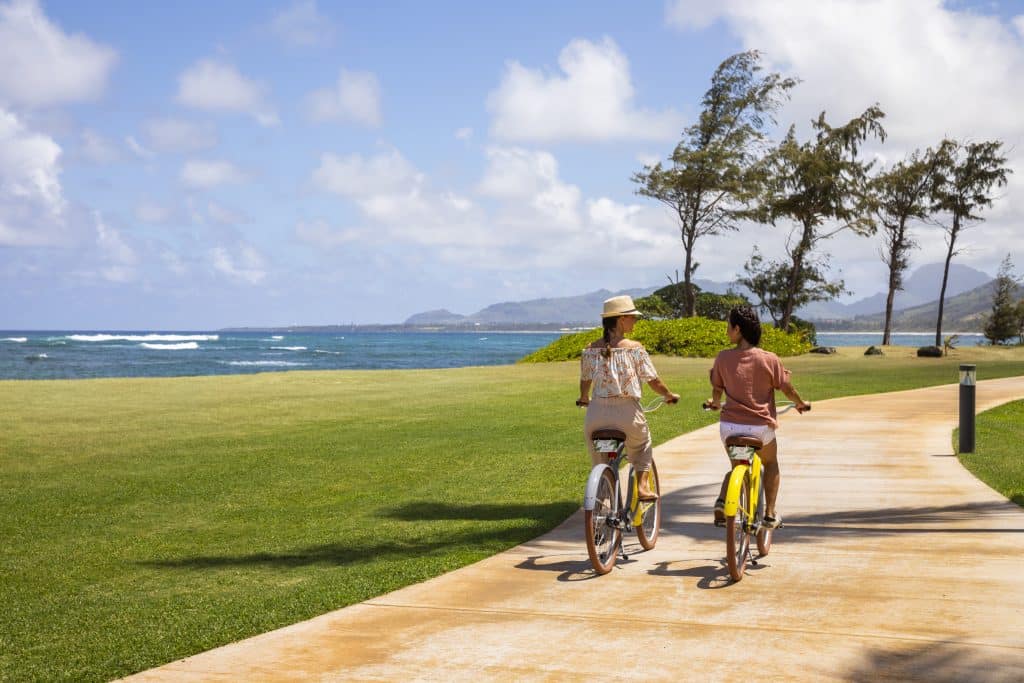 a pair riding bikes on island bike path at Sheraton Kauai Coconut Beach Resort