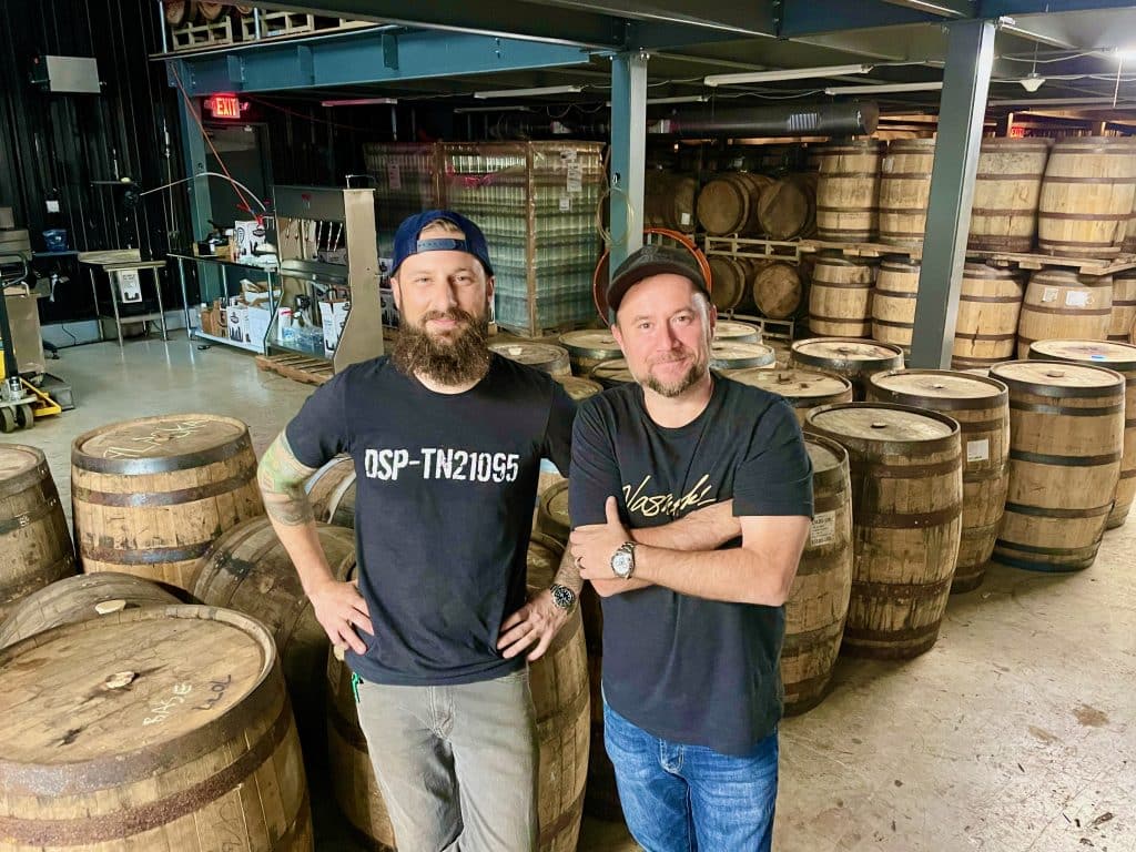 two men in front of barrells
