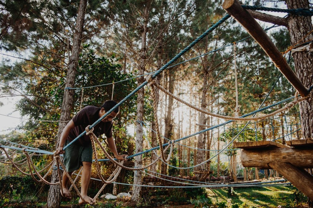 man walking on ropes in forest