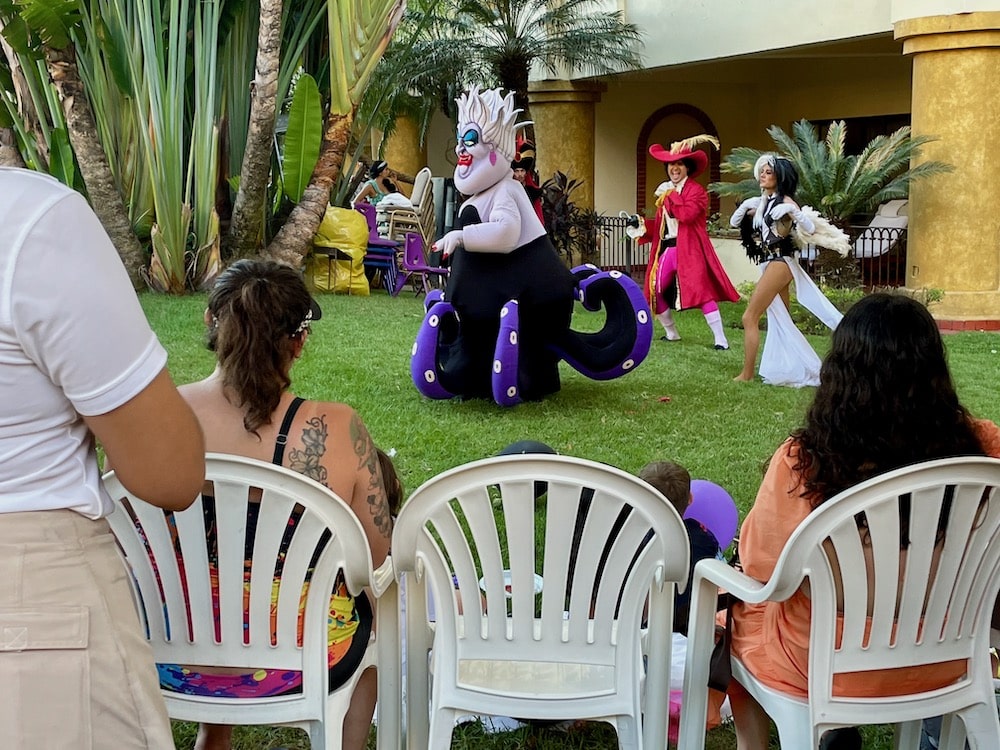 Disney characters from Little Mermaid perform on lawn.