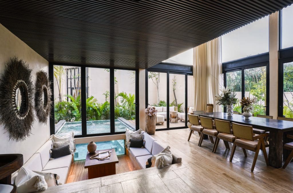 room with wall of windows and hot tub inside, pool outside