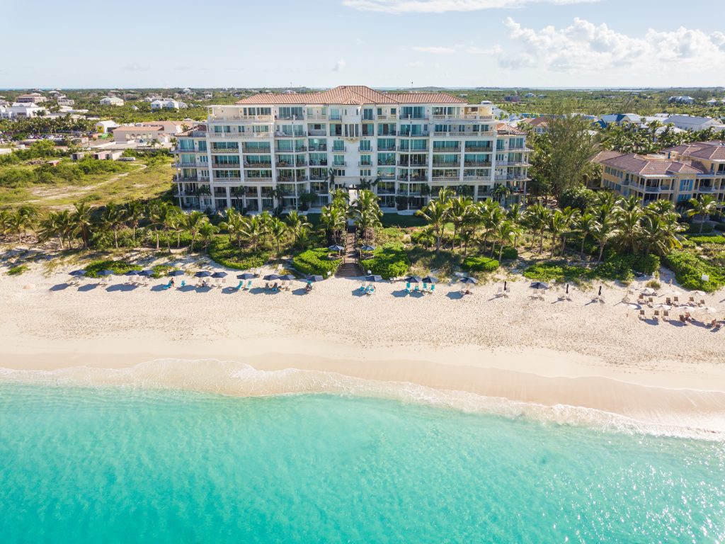 aerial of blue ocean with white hotel on land