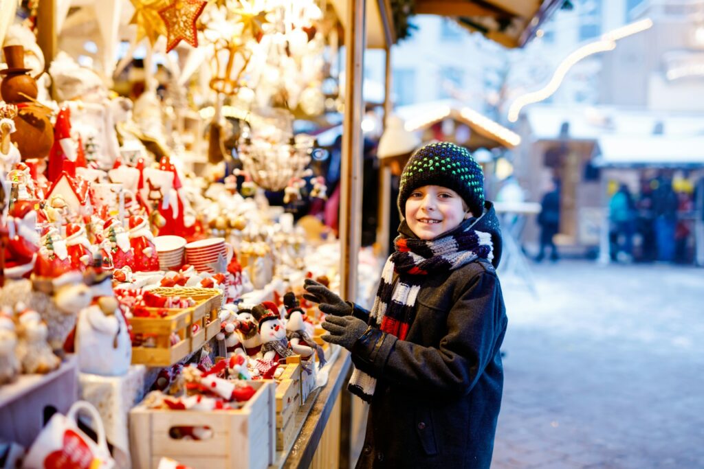 boy smiling at camera by lit up christmas stall