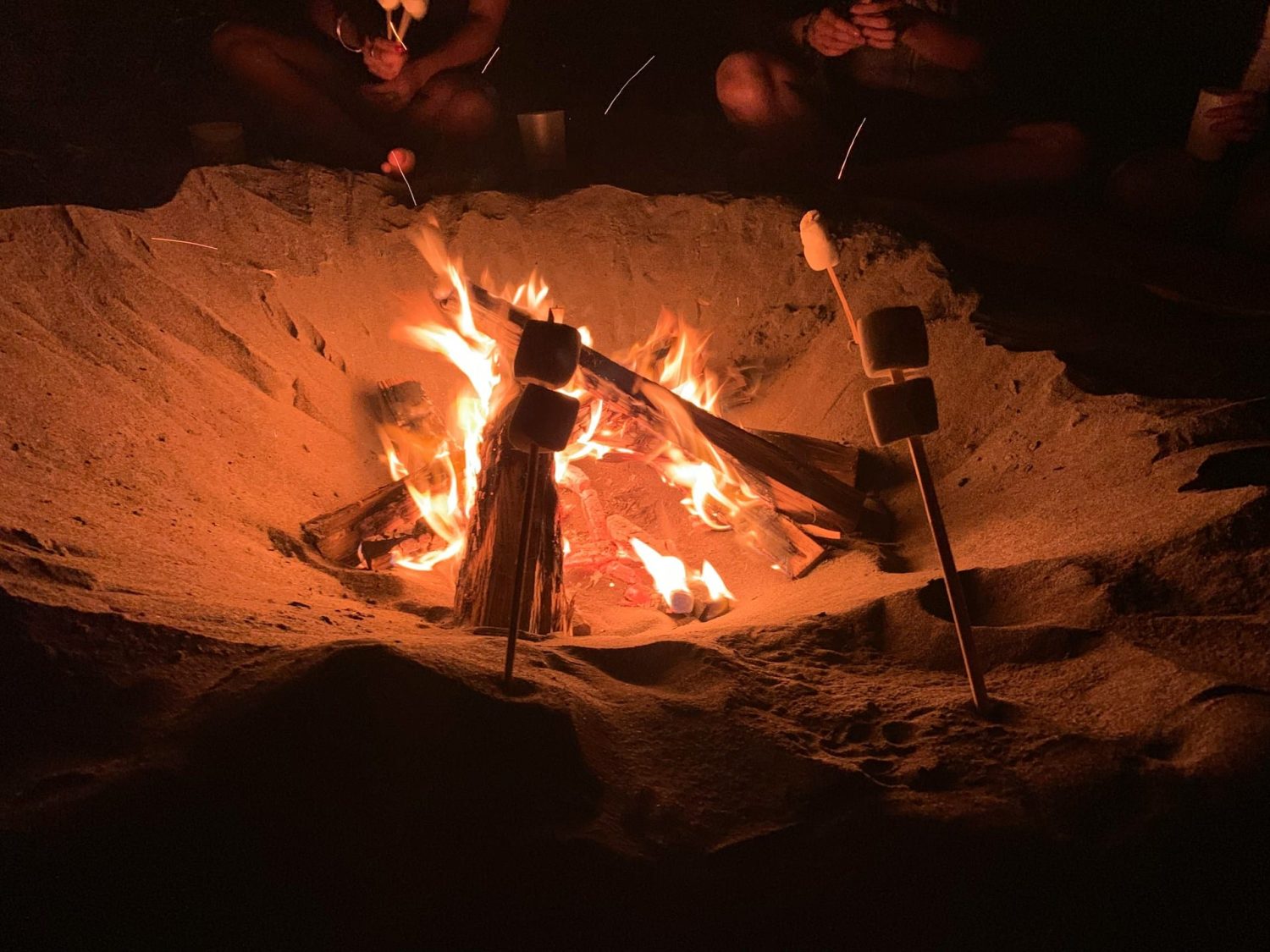 Family roasting marshmallows over a fire pit on the beach. Best beaches in Orange County.