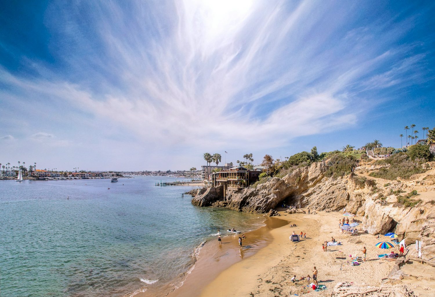 Corona del mar state beach park, with natural cliffs and people playing in the sand. Best Orange County Beaches.
