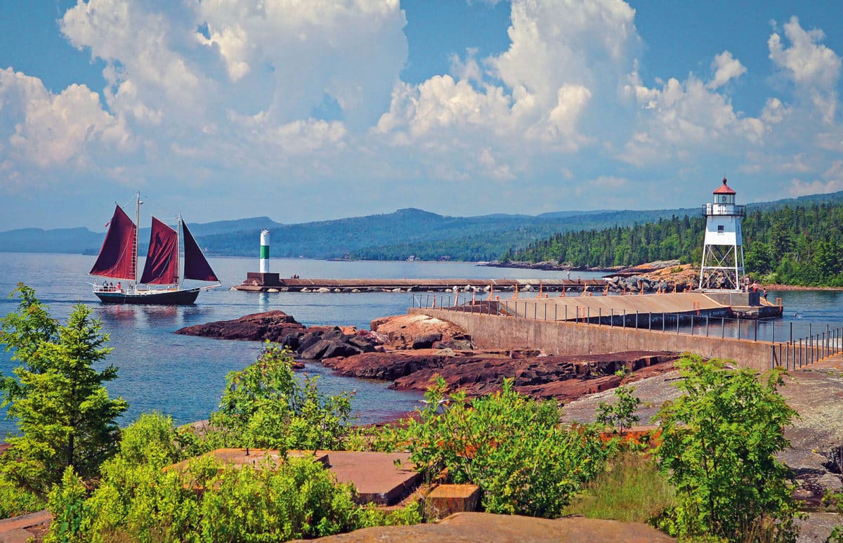 Sailboat and lighthouse surrounded by breakwall. Grand Marais with kids.