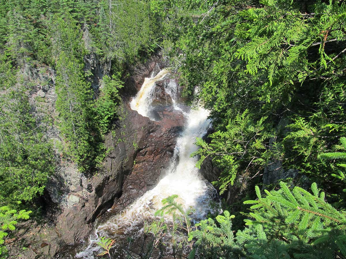 Upper Falls of Devil's Kettle surrounded by greenery. Grand Marais with kids. 