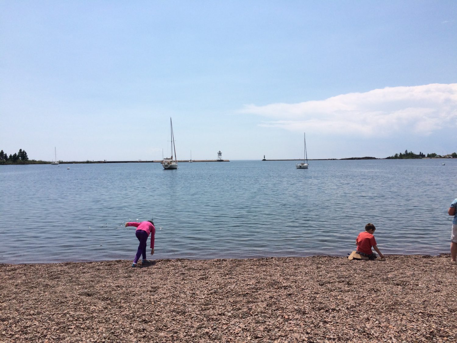 Kids skipping rocks on beach in the harbor. Grand Marais with kids.