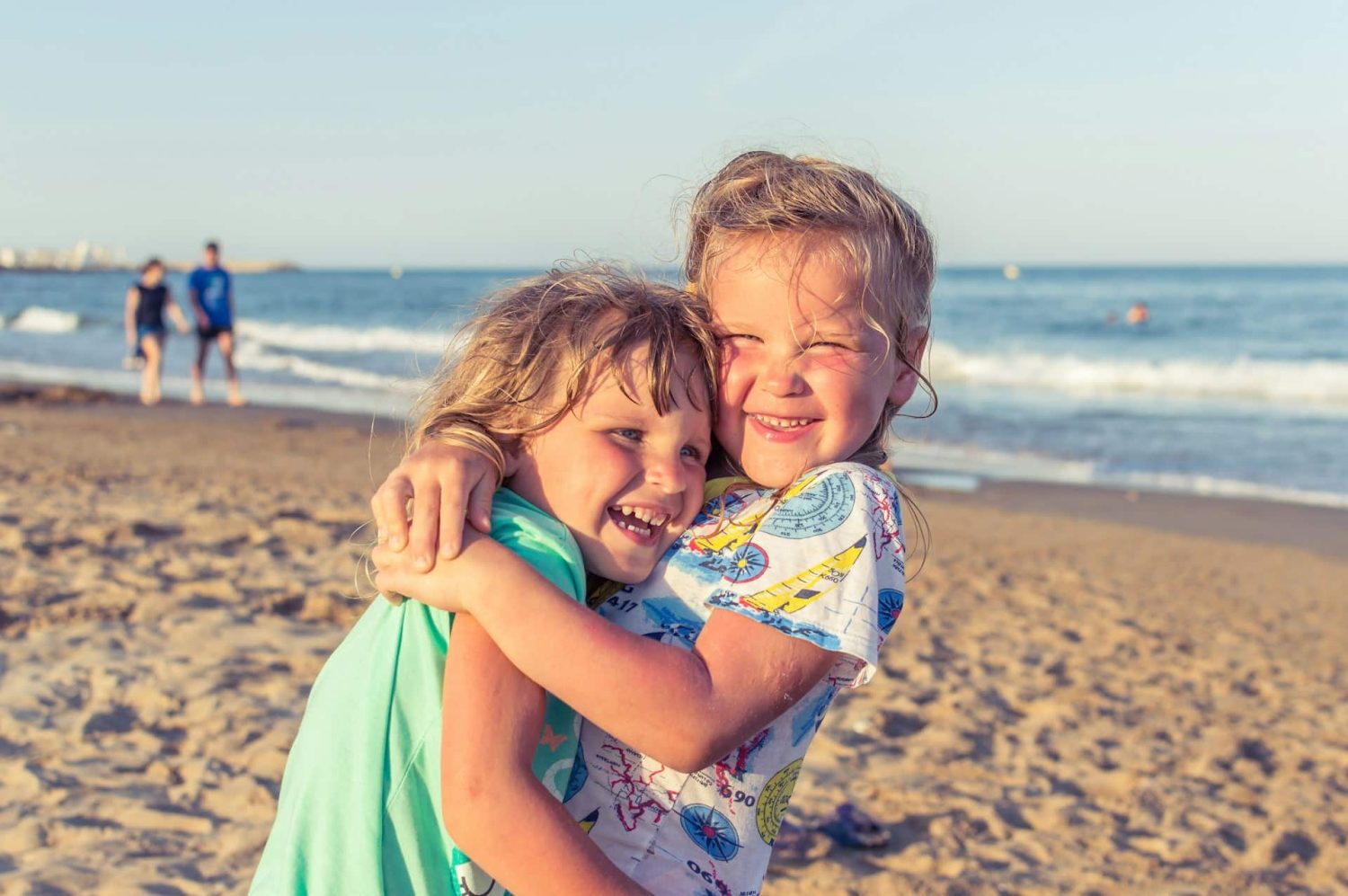 Siblings hugging each other on the beach. Best all-inclusive kid-friendly resorts in Florida.