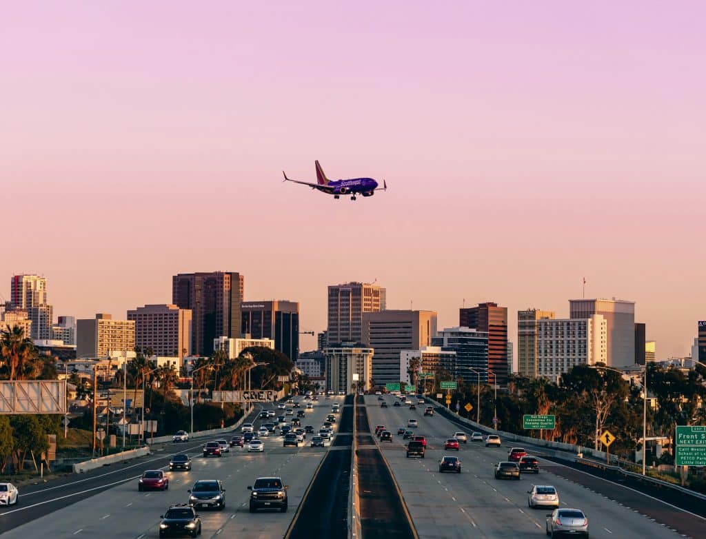 Airplane descending into San Diego over the city, with views of the skyline as it approaches the airport.