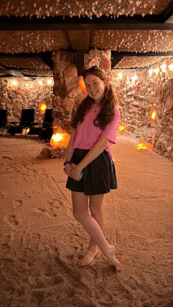 Girl relaxing inside a Himalayan salt cave, surrounded by pink salt walls and glowing ambient lighting, enjoying a calm and peaceful 45-minute session.