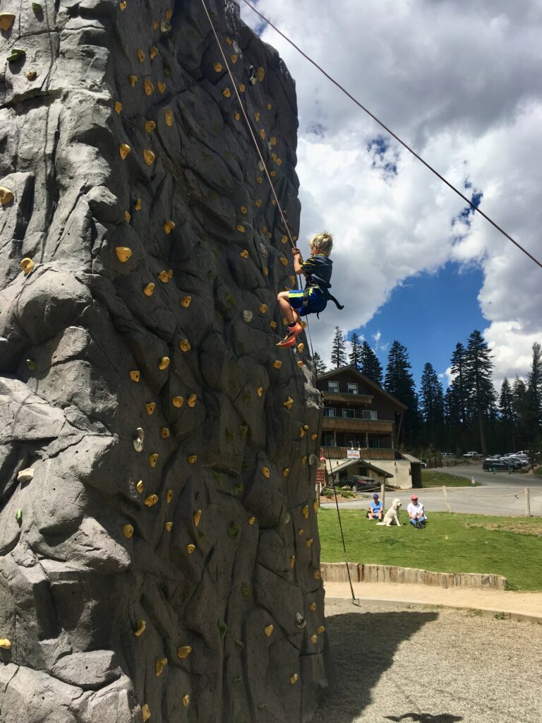 boy climbing tall rock wall