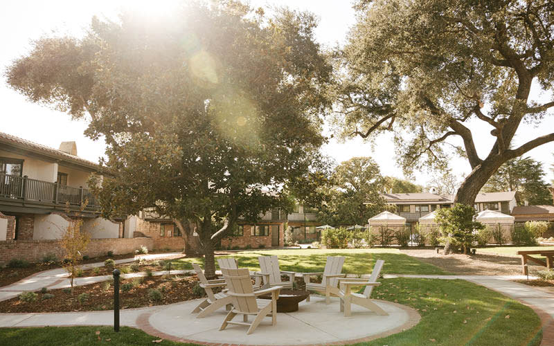 Outdoor view of the Paso Robles Inn grounds, featuring landscaped gardens, shaded walkways, and seating areas designed for relaxation