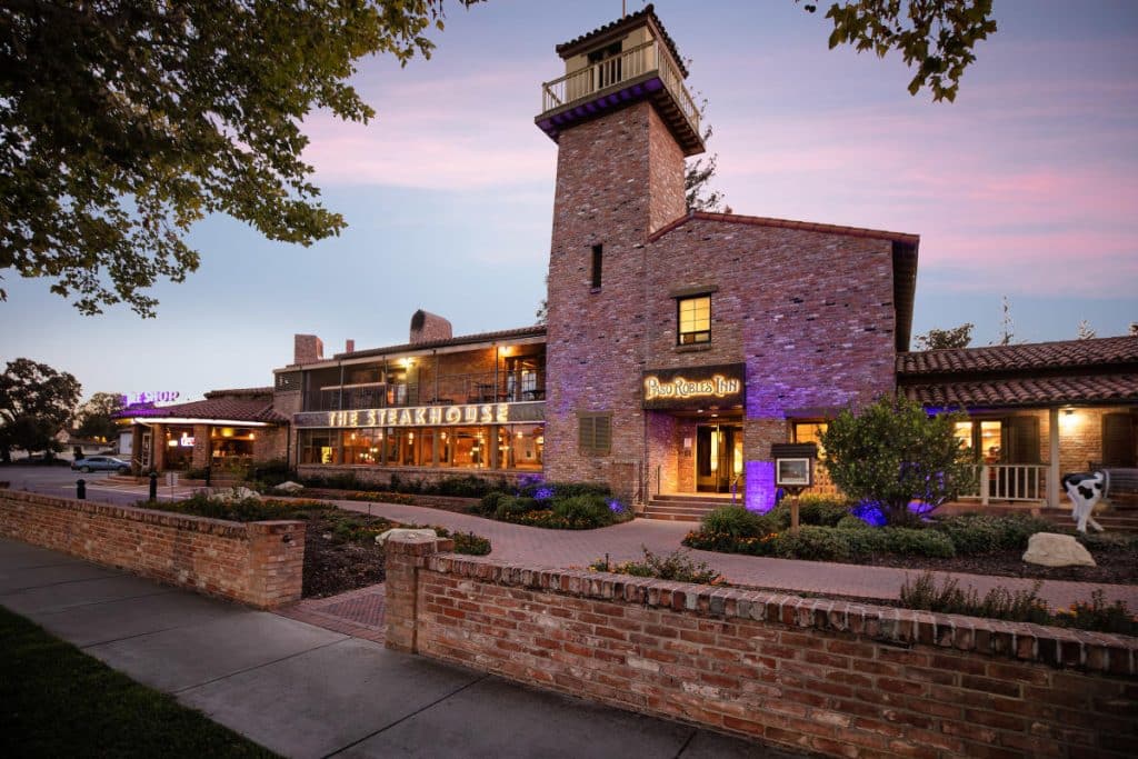 Exterior view of the historic Paso Robles Inn, showing its classic architecture, balconies, and courtyard setting, located beside the downtown square.