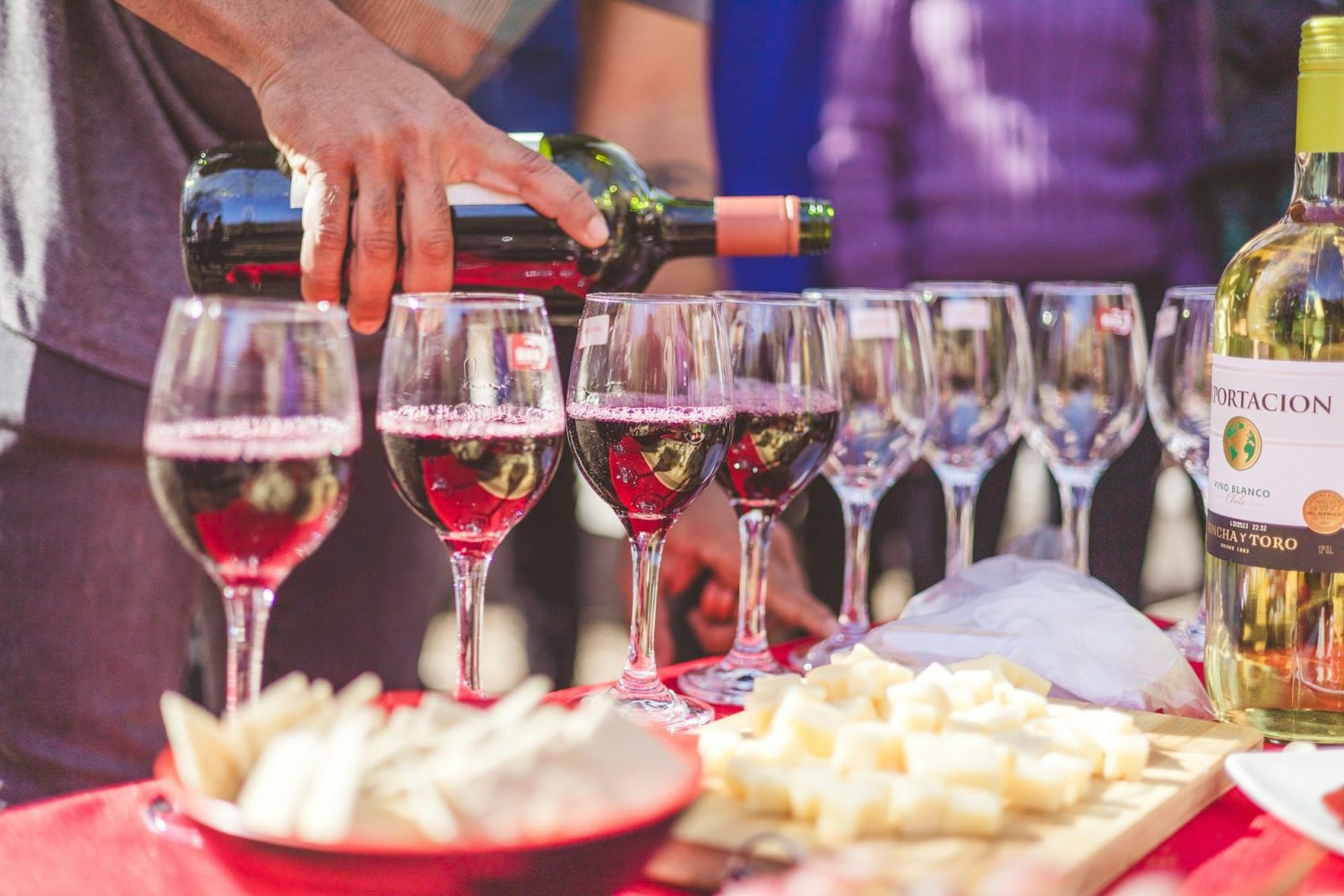 Man pouring several glasses of wine for tasting with appetizers. California wine festivals.