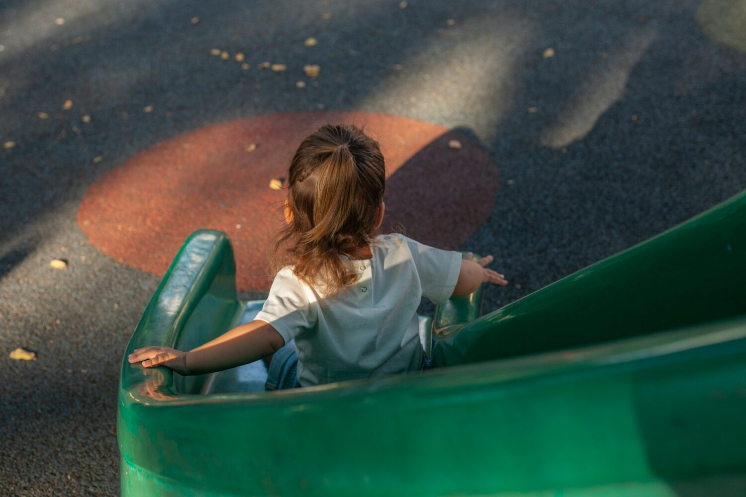 Girl sliding down green slide. Things to do in Columbus, Ohio with kids.