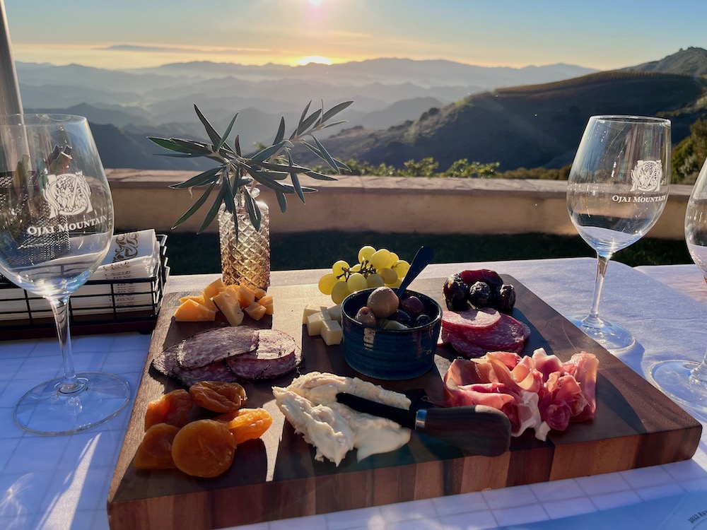 charcuterie board with wine glasses overlooking mountain ridge