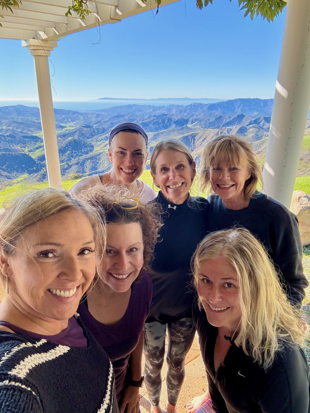 women huddled and smiling with mountain valley view