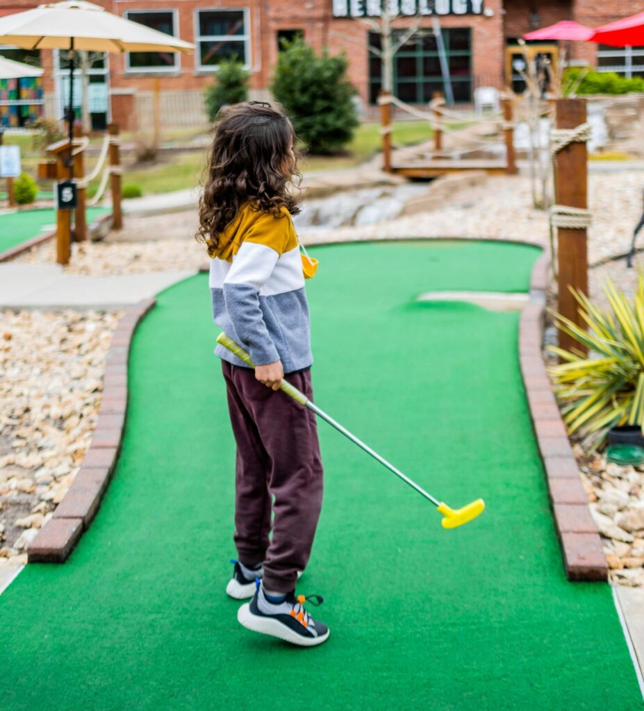 Young girl playing mini golf.