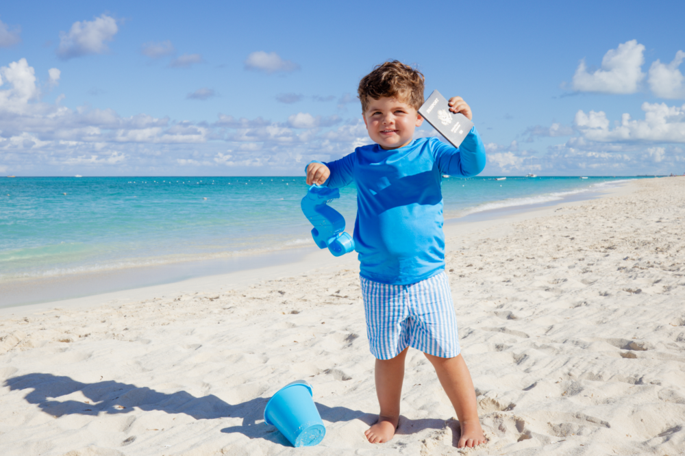 toddler holding passport on tropical beach
