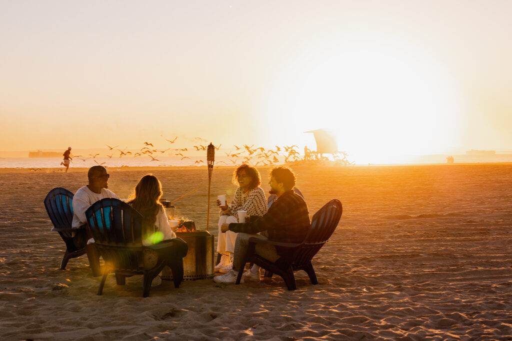 four people sitting on a sandy beach