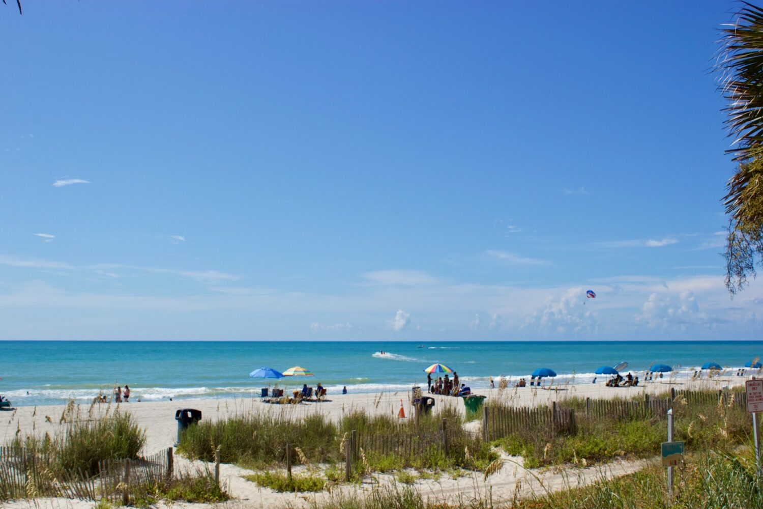 People on a beach under umbrellas. Oceanfront family resorts in Myrtle Beach.