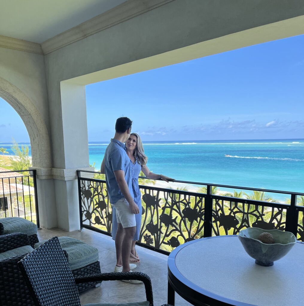 couple standing on balcony overlooking tropical beach