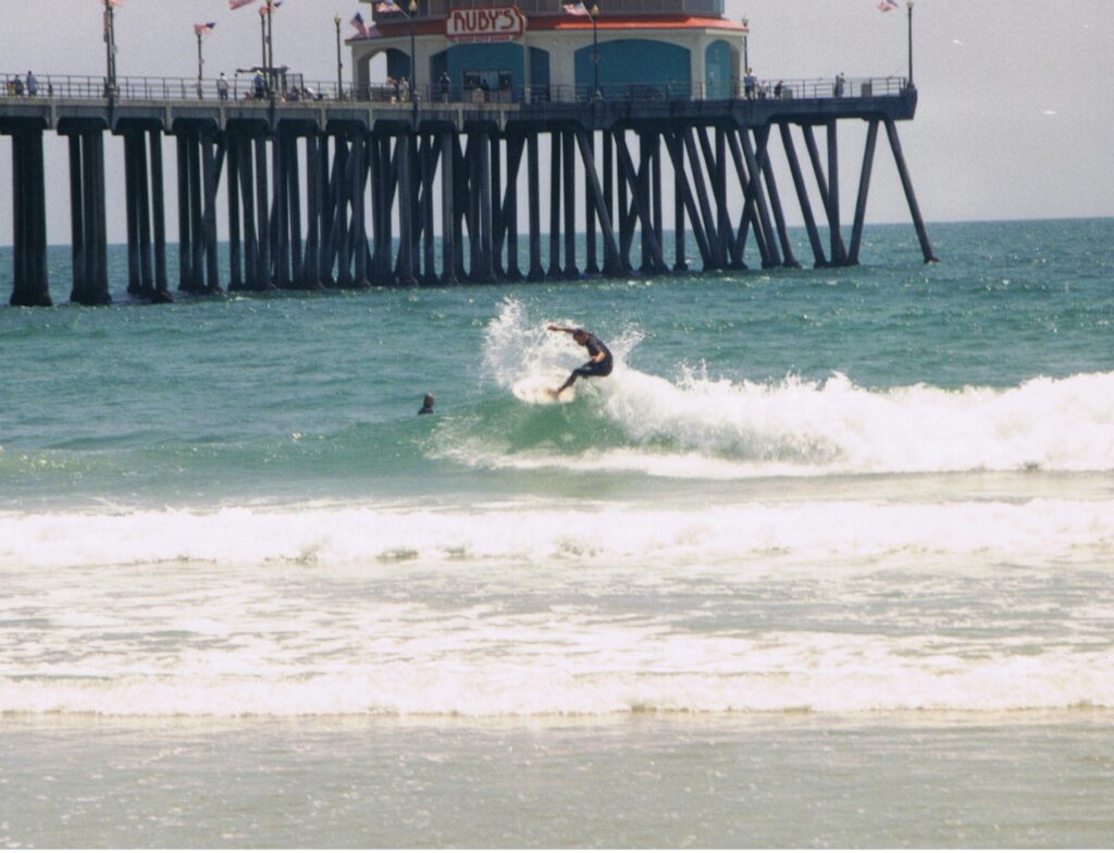 Surfer in the water by the pier.