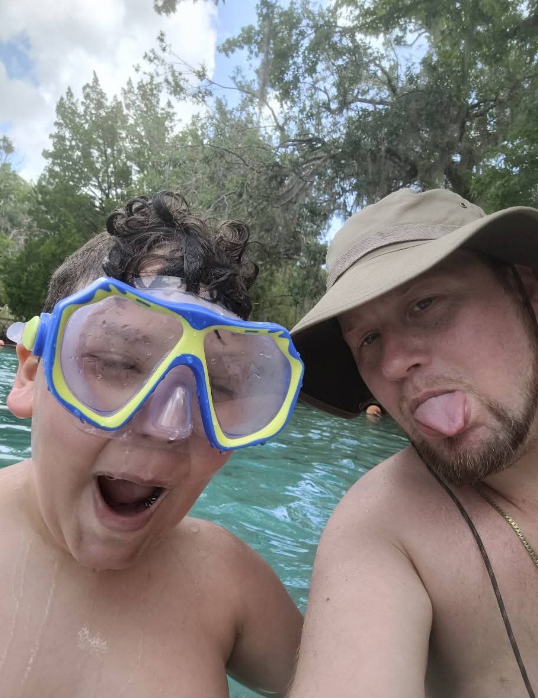 Man and boy making faces together in front of crystal clear waters and scenic background. Florida's hot springs. Natural springs in Florida. 