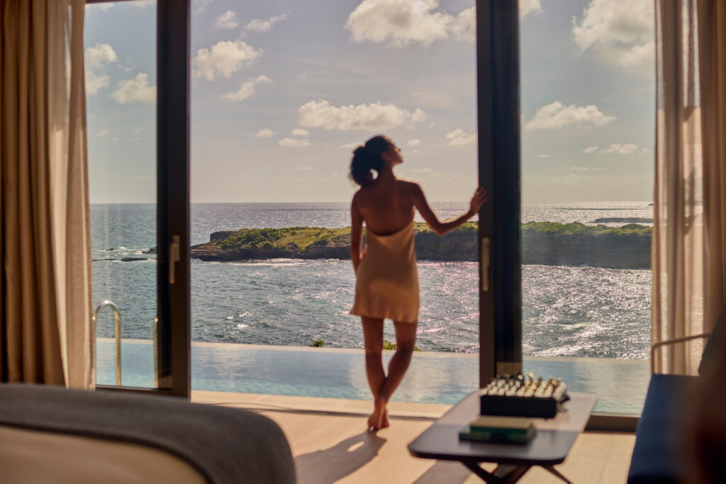 woman looking out glass wall toward water