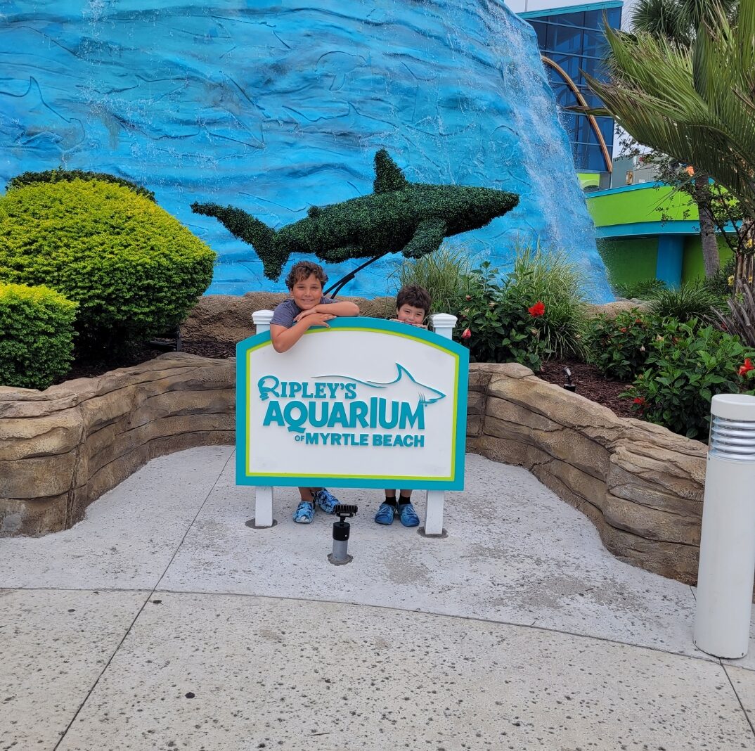 Boys smiling by sign at Ripley's Aquarium of Myrtle Beach. Best aquariums in the U.S.
