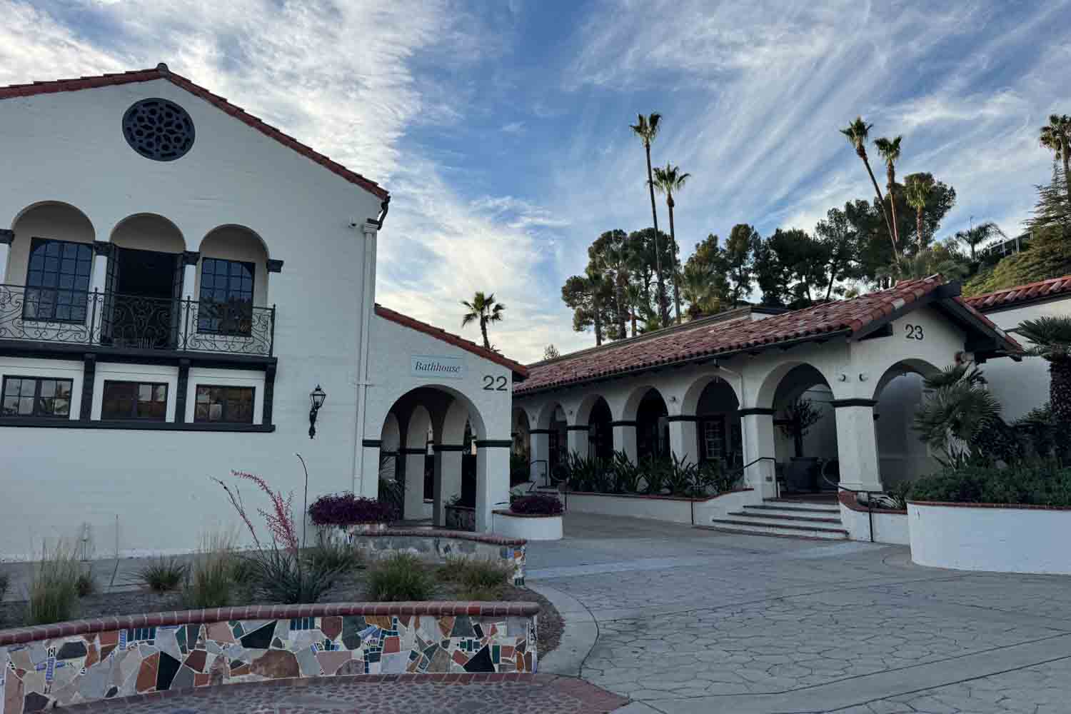 Spanish style bathhouse buildings with white walls. Red tile roofs. Arched entrances. And the numbers “22” and “23” on the exterior walls.