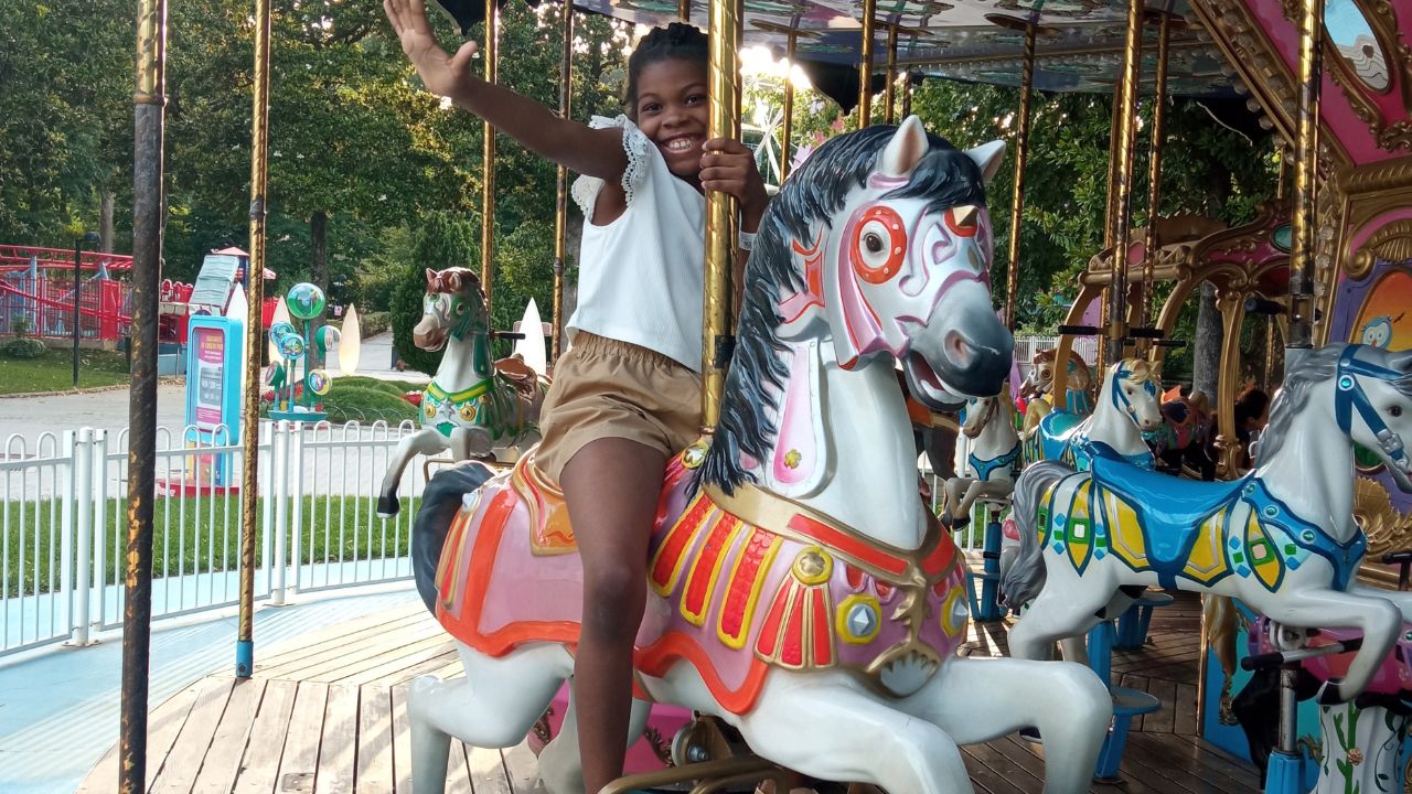 Young girl riding the merry go round at an amusement park in Rome