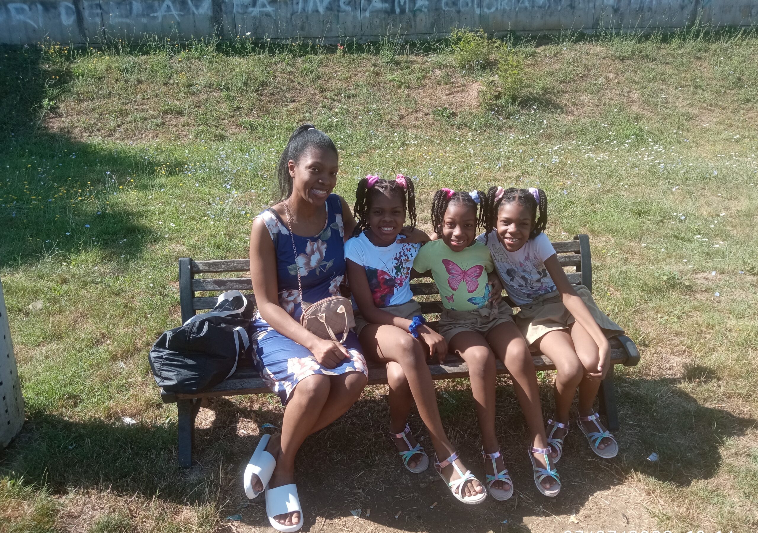 Mom and daughters sitting on a park bench near MagicLand amusement park in Rome