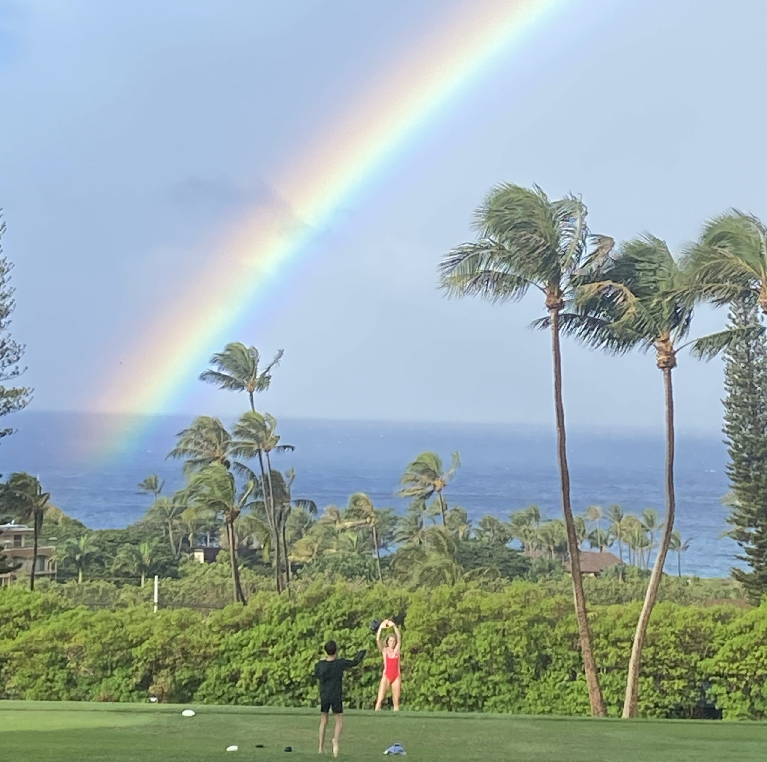 Rainbow over kids playing in the grass.