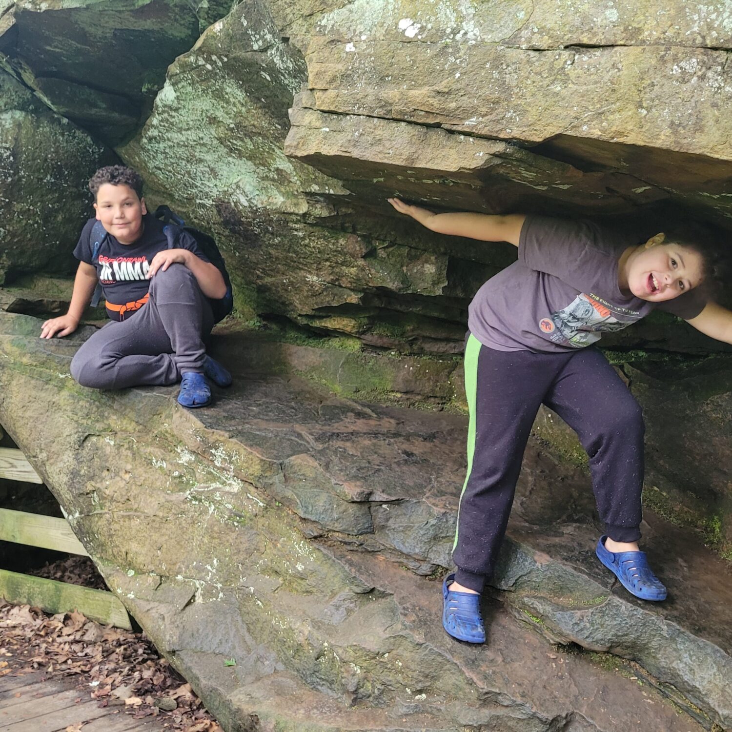 Two boys posing on a rock ledge in the woods. Cuyahoga Valley National Park for families. 