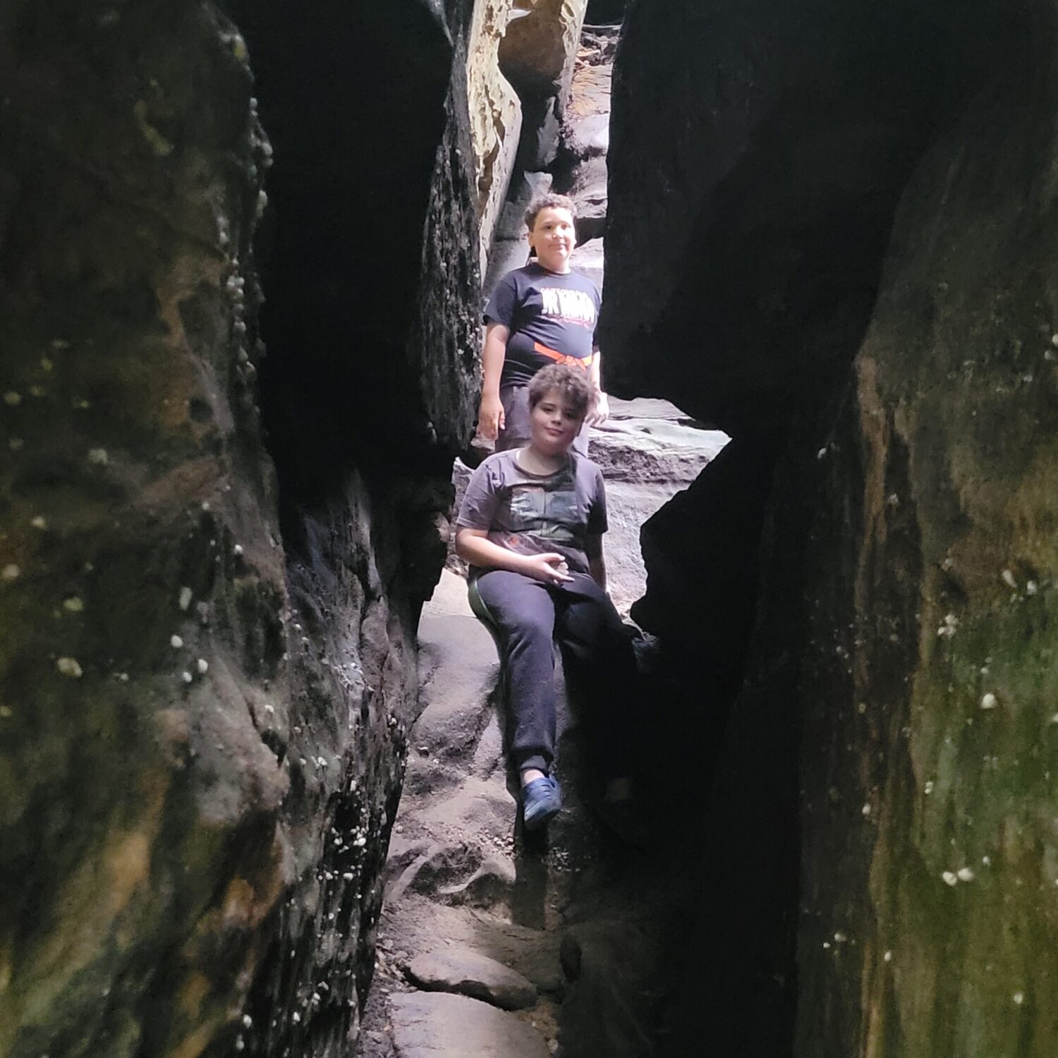 Two boys in crevice through rocks on Ledges Trail. Cuyahoga Valley National Park for Families. 