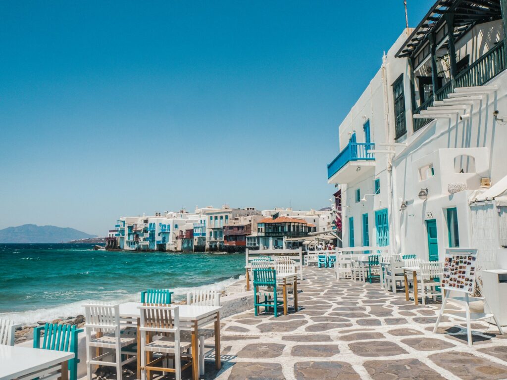 blue and white buildings on right and blue ocean on left in Greece