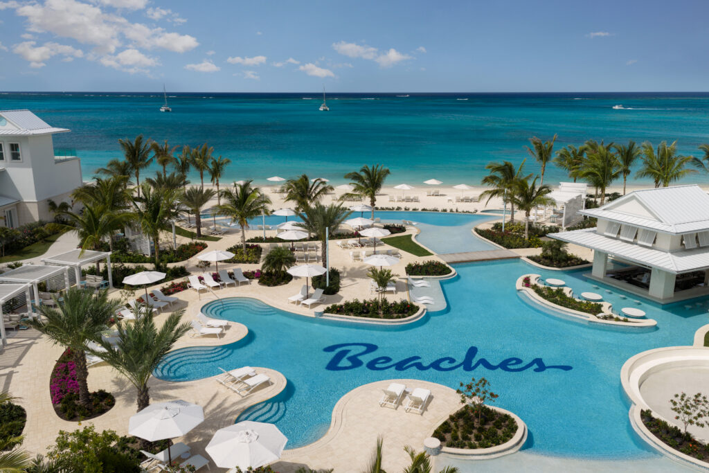 Beaches Resort pool with lounge chairs surrounding it with blue ocean in background.