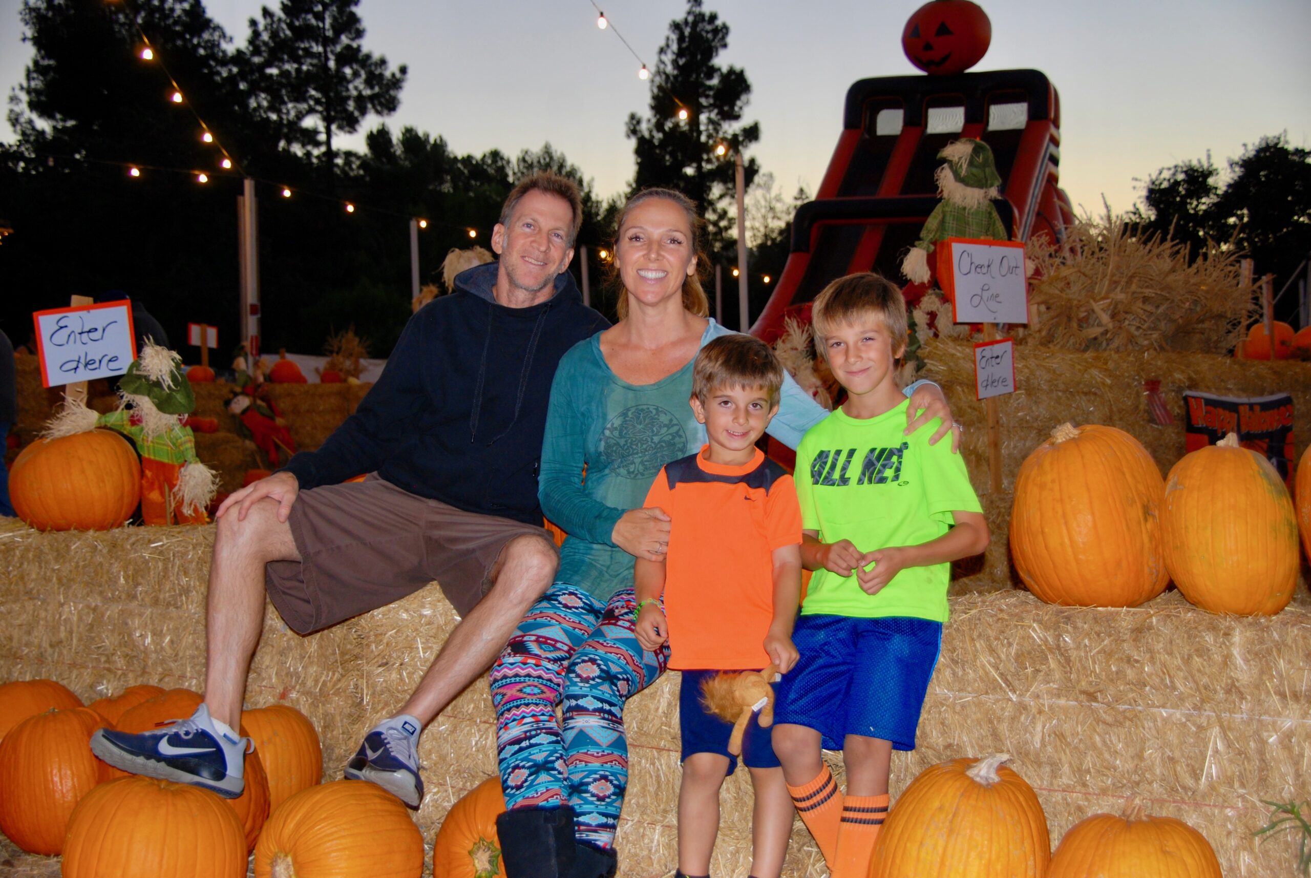 Family sitting on bales of hay at pumpkin patch.