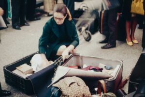 woman rearranging suitcases at airport